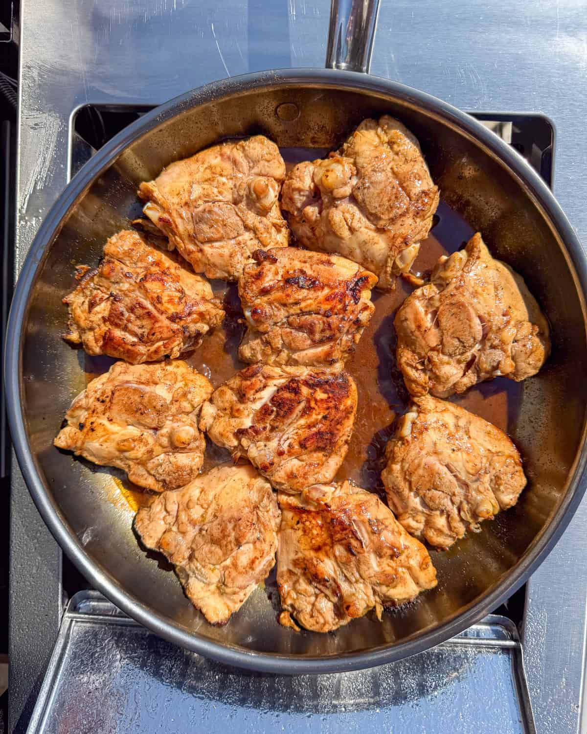 Seared chicken thighs sauce, skin side down in a skillet.