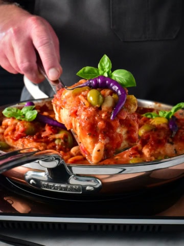 Lifting a piece of poached halibut out of a skillet.