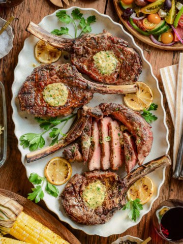 Four grilled veal chops on a platter served family style.