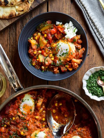 A serving of summer vegetable shakshuka with a baked egg and feta in a bowl.