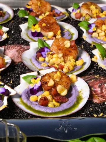 A tray filled with seared scallops with cauliflower puree and pancetta.