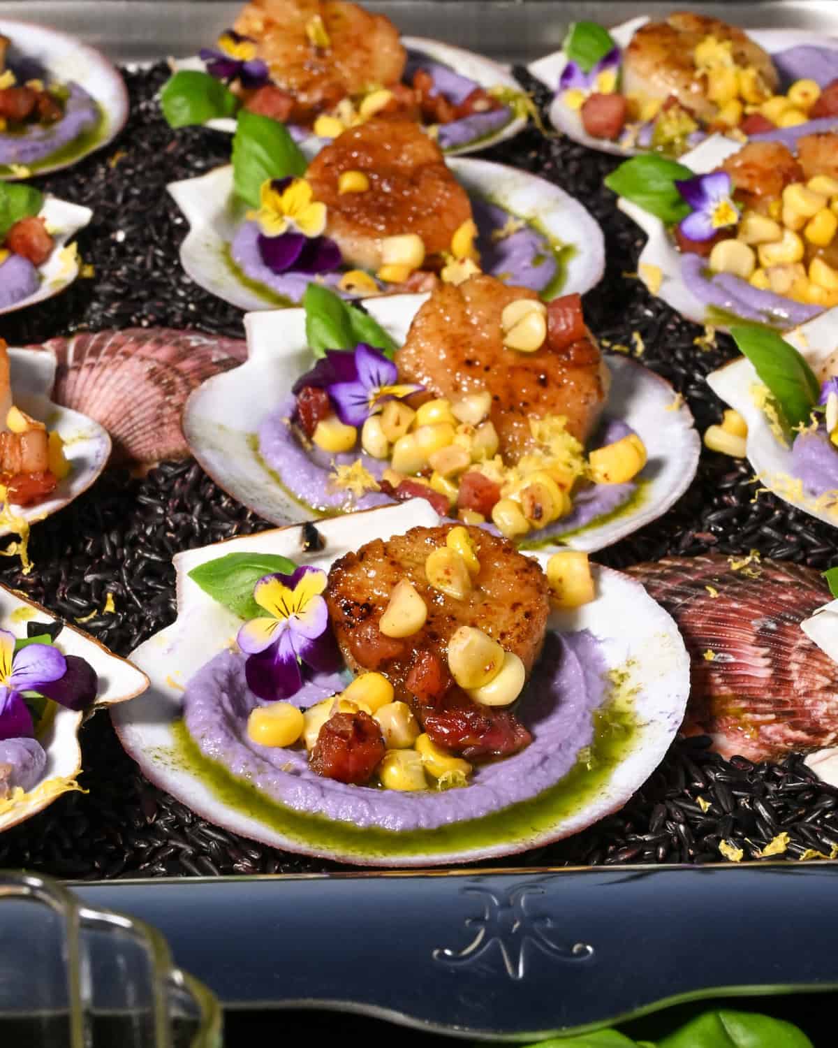 A tray filled with seared scallops with cauliflower puree and pancetta.