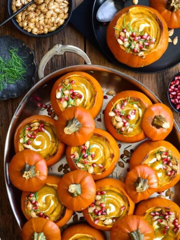An oval pan with several mini pumpkins served with a creamy pumpkin soup. Served with toppings, plus more on the side.