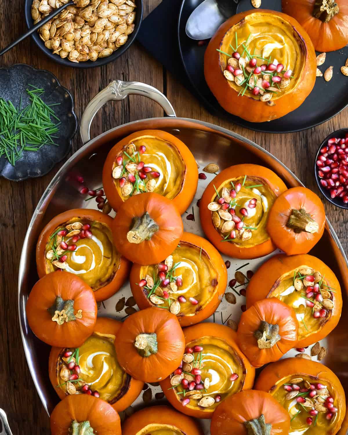 An oval pan with several mini pumpkins served with a creamy pumpkin soup. Served with toppings, plus more on the side.
