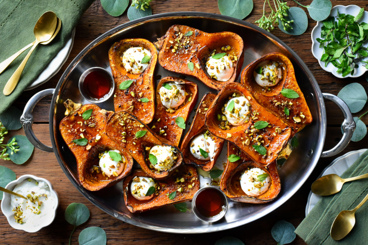 A platter of roasted Honeynut squash brulee topped with labneh, maple drizzle, mint and crushed pistachios.