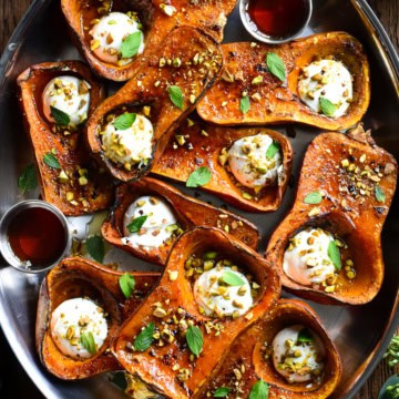 A platter of roasted Honeynut squash brulee topped with labneh, maple drizzle, mint and crushed pistachios.