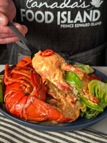 A plated coconut curry lobster with veggies and rice.