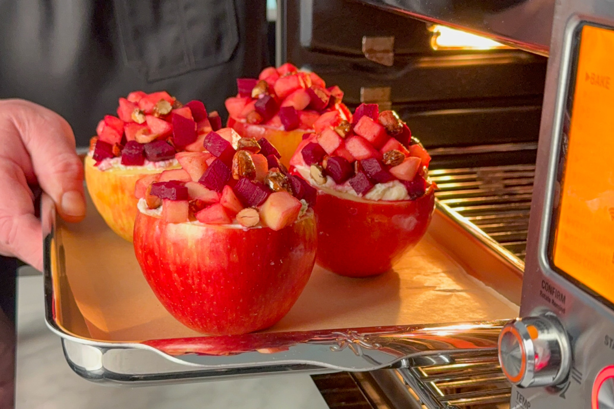 Placing a tray of stuffed baked apples into a smart oven.