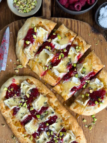 Two Flatbread Appetizers with Camembert & Raspberry Prosecco Jam, one is cut into pieces.