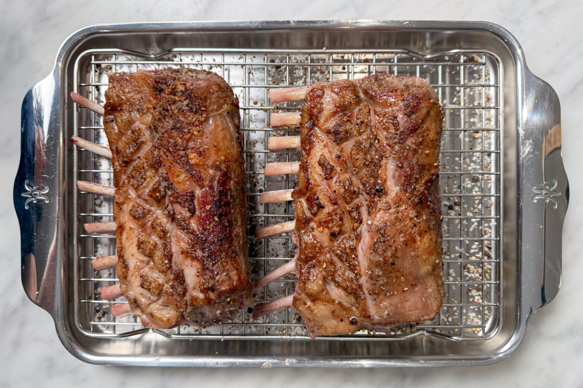 Two seared frenched lamb racks on a rack.