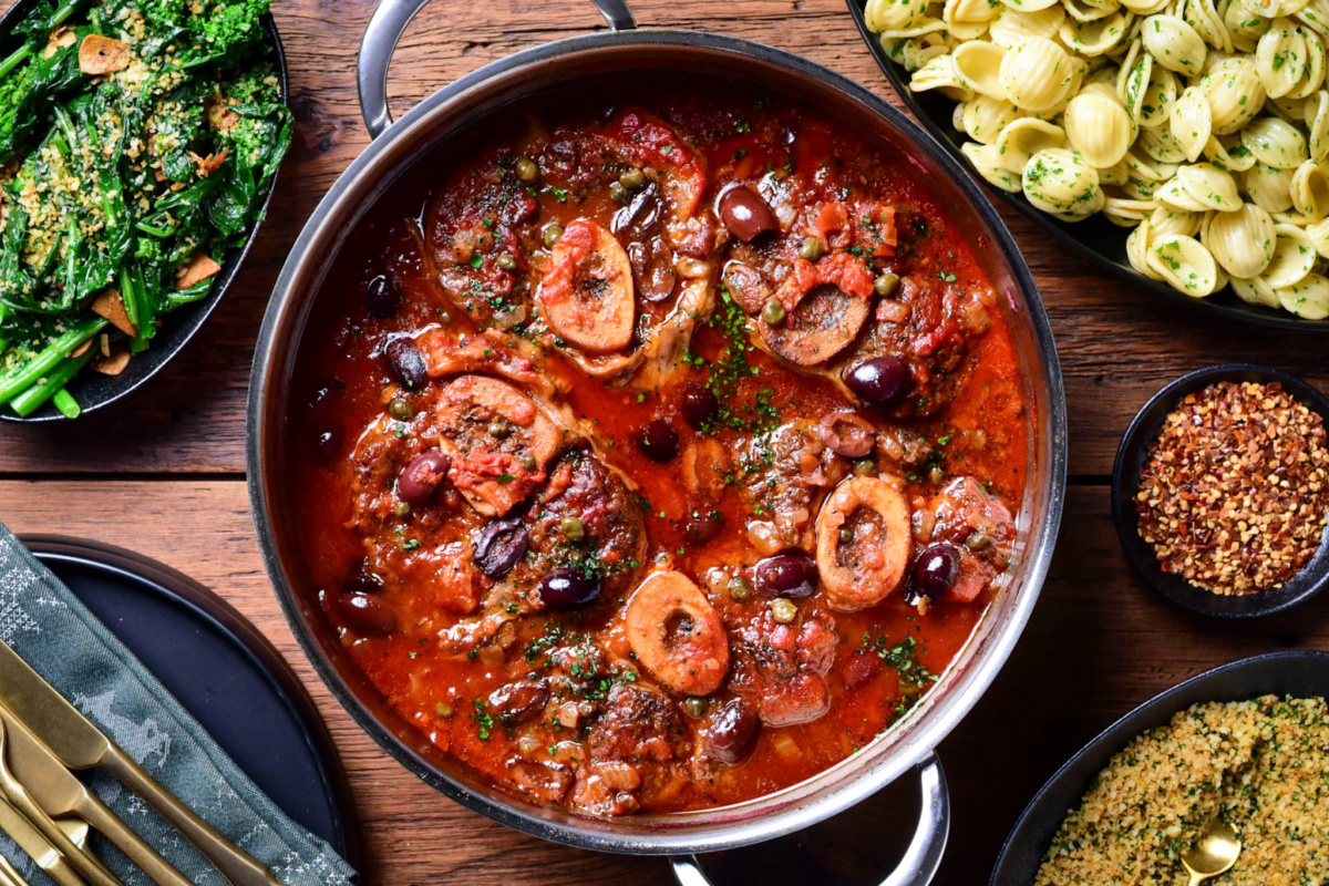 A pot of braised veal osso buco with Puttanesca sauce and served with “Mezzanotte” orecchiette, garlicky rapini and lemon-parsley breadcrumbs.