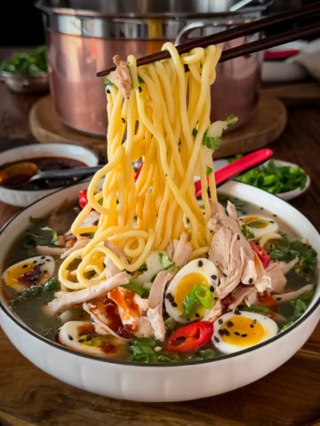 A noodle pull from a bowl of ginger chicken ramen soup with bok choy, ramen-style noodles and jammy quail eggs.