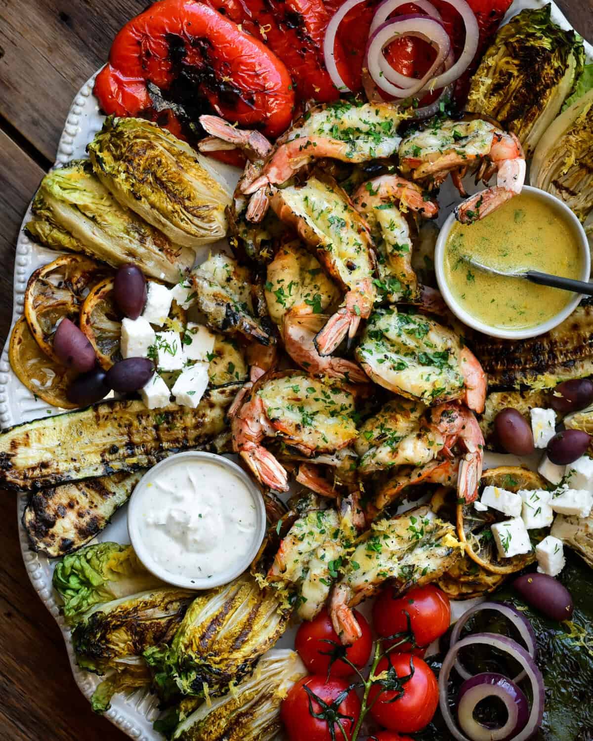 A platter with a butterflied grilled shrimp salad with grilled veggies, and served with a Lemon-Dijon Dressing.