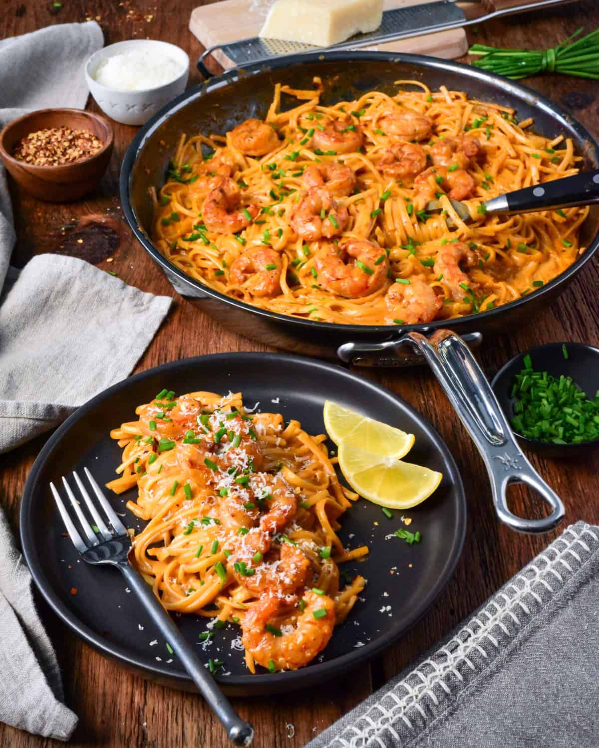 A plate of skillet of creamy spicy Canjun shrimp linguine served with chopped chives and lemon slices.