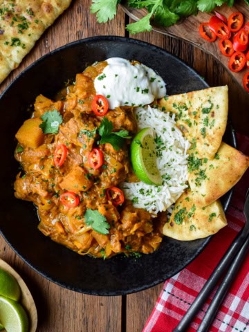 A bowl of beef and vegetable coconut curry served with basmati rice, coconut rice and garlic naan.