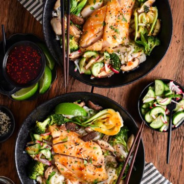 Two bowls of miso black cod served with rice noodles and vegetables.