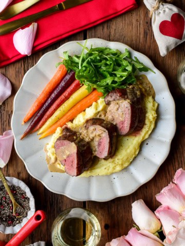 Three medallions of reversed seared veal tenderloin served with a Dijon Cognac sauce, potato puree, carrots and arugula for a Valentine's Day recipe.