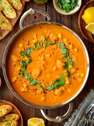 A large pot of butter bean and carrot soup that is topped with microgreen.