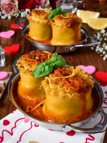 Two individual seafood lasagna roll ups with a lobster bisque sauce served in au gratins for Valentine's Day.