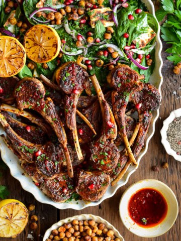 A platter half full with harissa lamb chops and the other half with a crispy chickpea & halloumi salad.