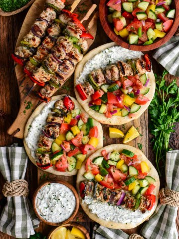 A pile of chicken souvlaki and three pitas loaded with chicken souvlaki, greenhouse salad and whipped feta tzatziki.