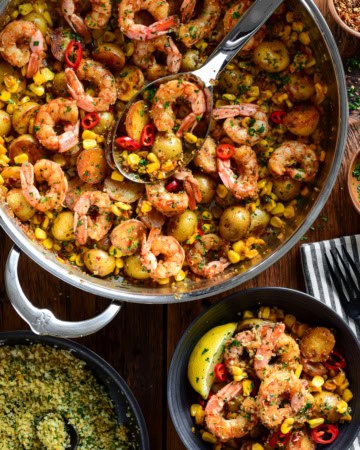 A skillet of spicy Calabrian shrimp with corn and potatoes. Served in a bowl with a lemon pangrattato sprinkled over it.