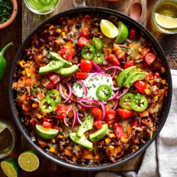 Fresh Mexican-style skillet with black beans, cherry tomatoes, avocado slices, red onions, and jalapeños garnished with lime wedges. Perfect for a flavourful, healthy meal or snack.