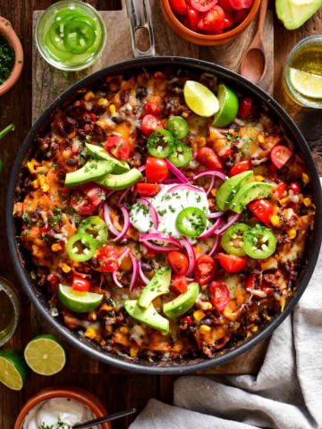 Fresh Mexican-style skillet with black beans, cherry tomatoes, avocado slices, red onions, and jalapeños garnished with lime wedges. Perfect for a flavourful, healthy meal or snack.