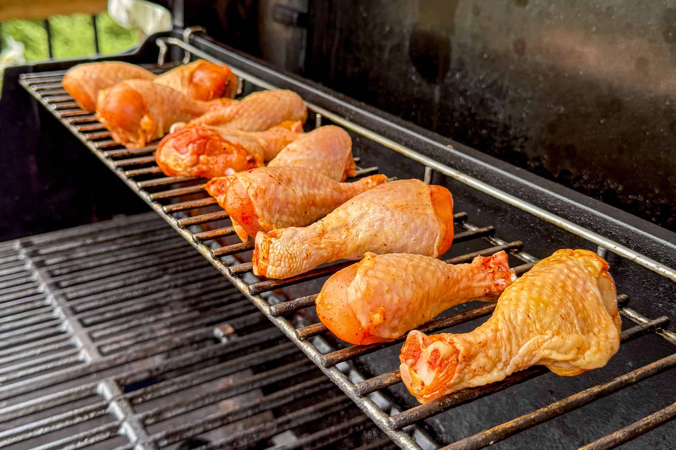 Season the chicken drumsticks, then place them on the top rack of the grill to cook.