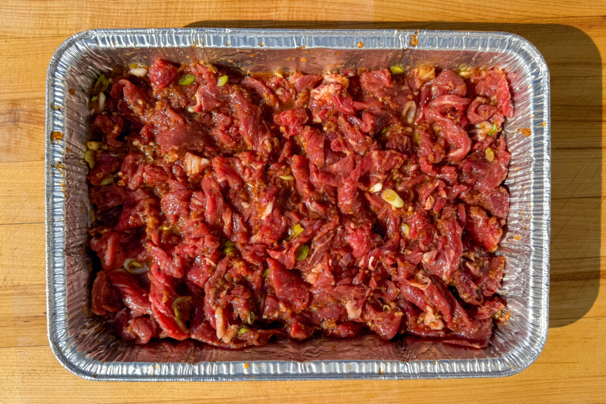 An aluminium tray with sliced beef marinating in a bulgogi marinade. 