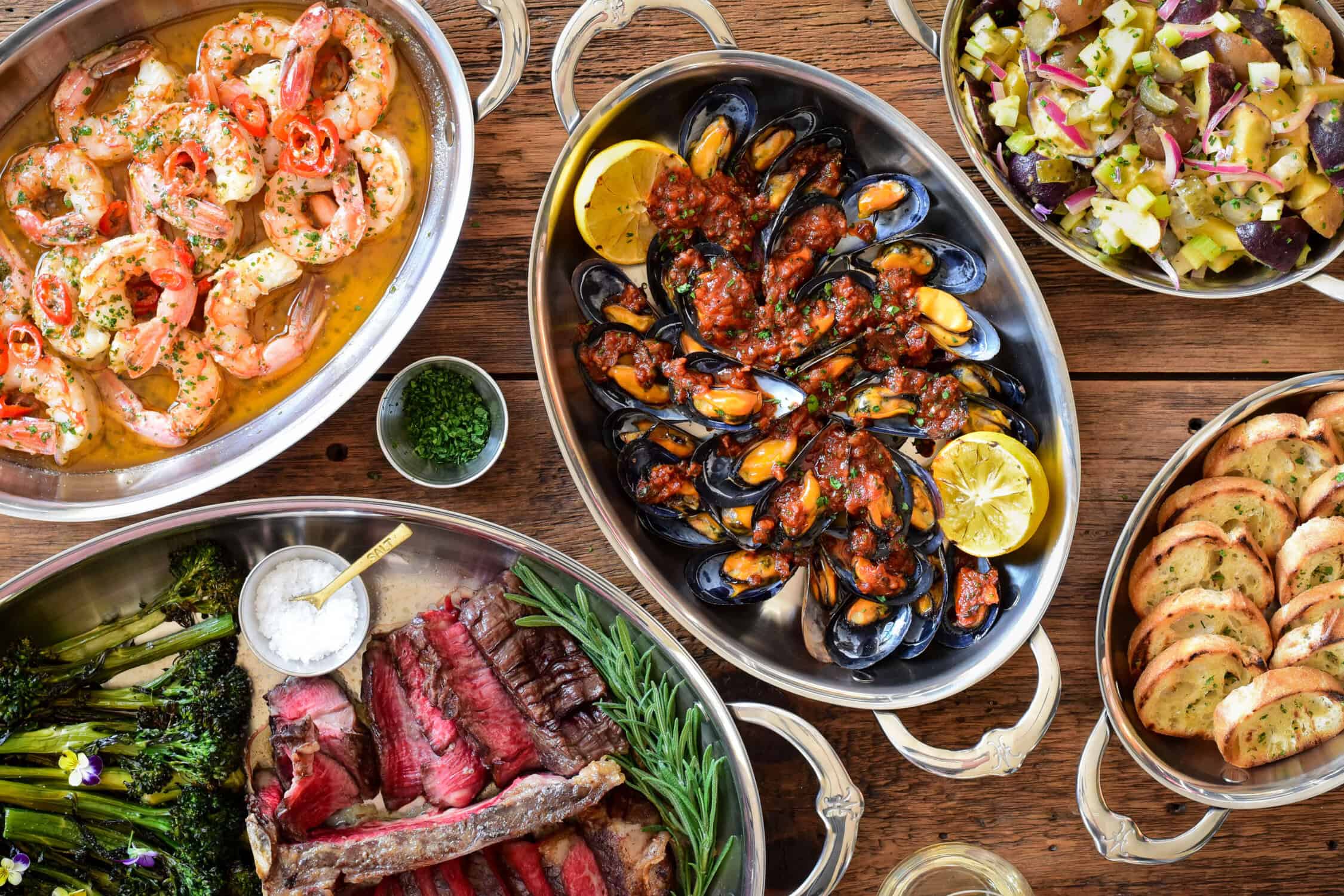 Served here alongside this Spanish-style Mejillones en Salsa Picante dish we served a Thick Cut Reverse Sear T-Bone, garlicky shrimp sautéed in olive oil, garlic and herbs, and a creamy Dill Pickle Potato Salad. Plenty of grilled toast was essential for soaking up every last bit of sauce.