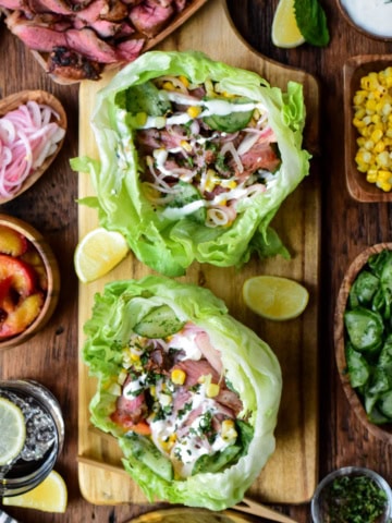 Fresh lettuce wraps with grilled lamb, vegetables, and flavorful sauces on a rustic wooden table. Perfect for healthy, delicious meals and meal prep.