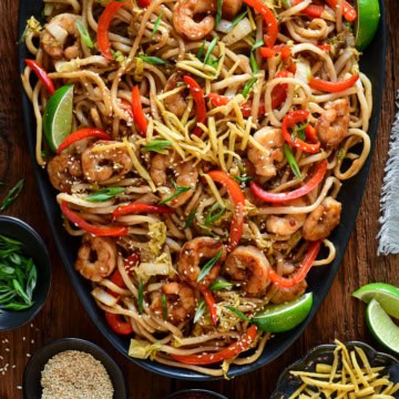 A platter of Sticky Soy Argentinian Shrimp & Fried Ginger Udon. Served with extra fried ginger, limes, sesame seeds and green onions.