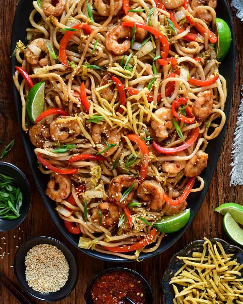 A platter of Sticky Soy Argentinian Shrimp & Fried Ginger Udon. Served with extra fried ginger, limes, sesame seeds and green onions.